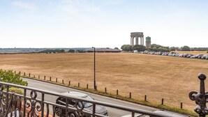 Un parking avec une rangée de voitures et, au loin, un grand château d’eau.