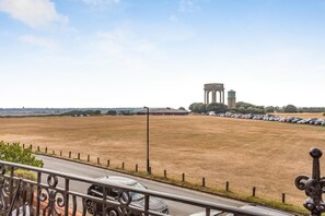 A parking lot with a row of cars and a large water tower in the distance. - 6 Bed in Southwold (oc-flgr) (Southwold)