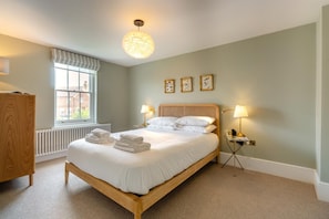 A neatly made bed with white linens, a wooden headboard, and a bedside lamp. - 6 Bed in Southwold (oc-flgr) (Southwold)