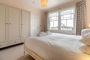 A hotel room with a large bed, a wardrobe, and a window with curtains. - 6 Bed in Southwold (oc-flgr) (Southwold)