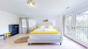 Een slaapkamer met een bed, nachtkastjes, een bureau en een raam met uitzicht.