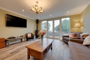 A living room with a flat-screen TV, a fireplace, a sofa, a coffee table, and a large window. - 8 Bed in Llanrhidian (oc-hh1235) (Llanrhidian)