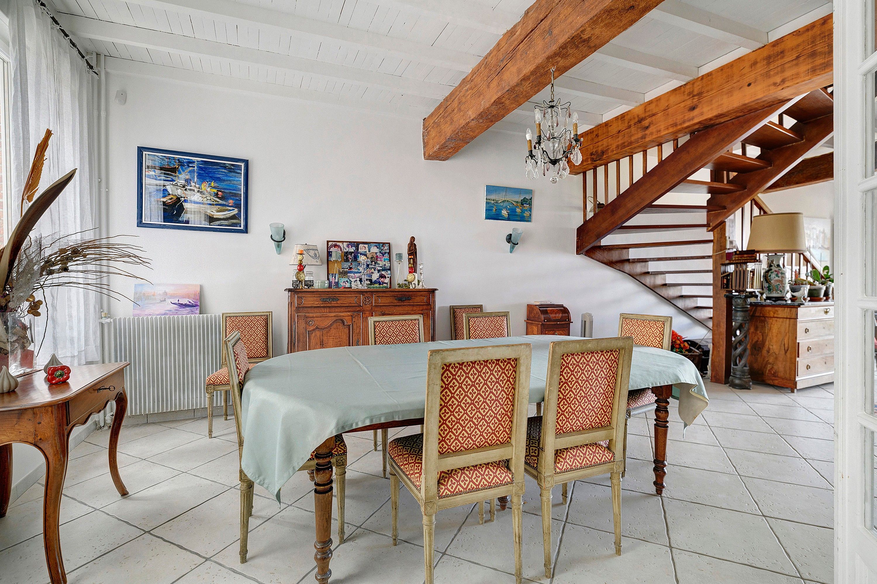 Ein Essbereich mit einem Holztisch, Stühlen, einer Kandelaber und einer Treppe.