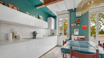 A kitchen with white cabinets, a tiled floor, and a dining area with a table covered in a blue tablecloth.