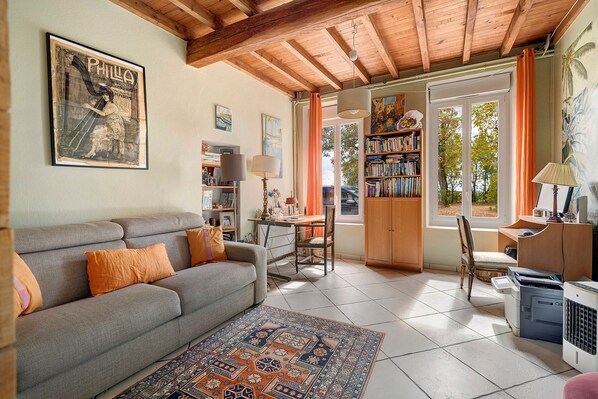 Un salon confortable avec un canapé, un tapis, une bibliothèque et un bureau avec un ordinateur.