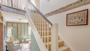 Een trap met een houten leuning en beklede treden met een beige vloerbedekking, die naar een verdieping leidt.