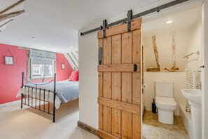 A bedroom with a bed, a sliding barn-style door, and a bathroom with a toilet and sink. - 1 Bed in Lavenham (oc-b27506) (Lavenham)