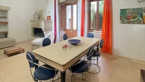 Ein Essbereich mit Tisch, Stühlen, einem Kamin und Blick ins Freie.