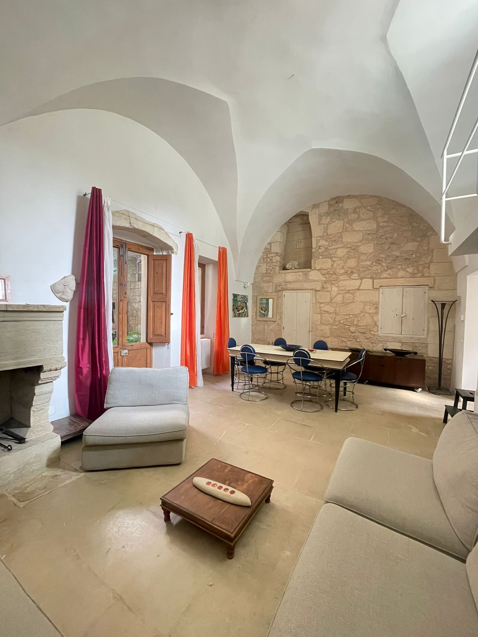 Un'ampia zona giorno con parete in pietra, un tavolo da pranzo con sedie e un divano.