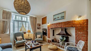 Un salon chaleureux avec une cheminée en briques, des sièges confortables et une grande fenêtre.