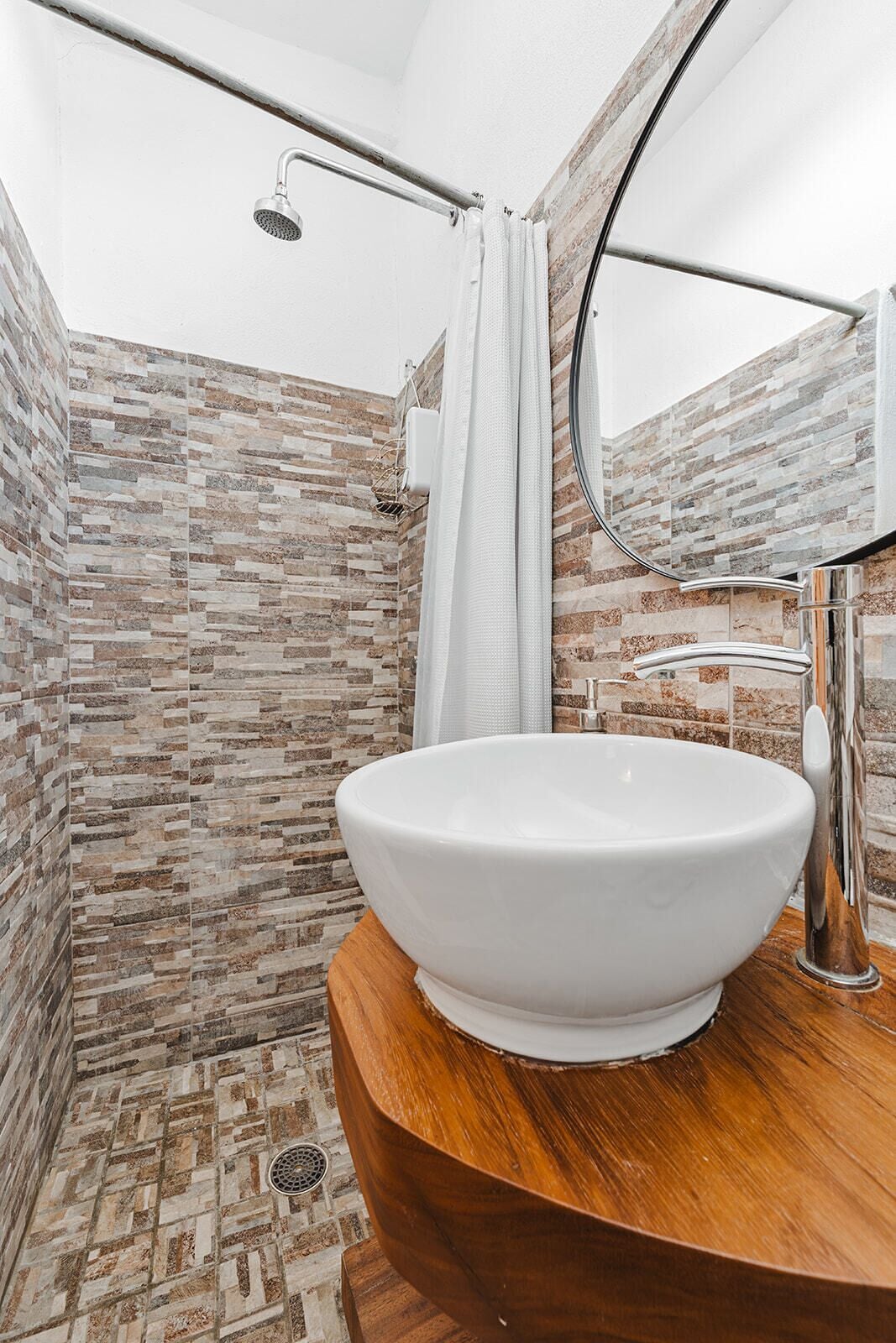 A bathroom with a large white sink, a shower with a glass door, and a mirror.