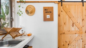 Eine Küche mit Holztür, Hut, Schild und Pflanze.