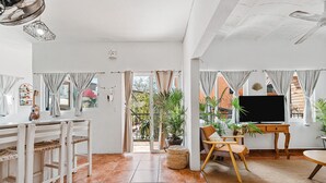 Ein geräumiger Wohnbereich mit Fernseher, Sitzgelegenheiten und Topfpflanzen.
