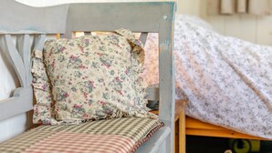 Una cama de madera con almohada estampada con flores y colcha a cuadros.