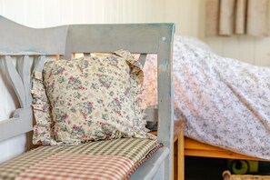 Ein hölzernes Bett mit einem blumigen Kopfkissen und einer karierten Bettdecke.