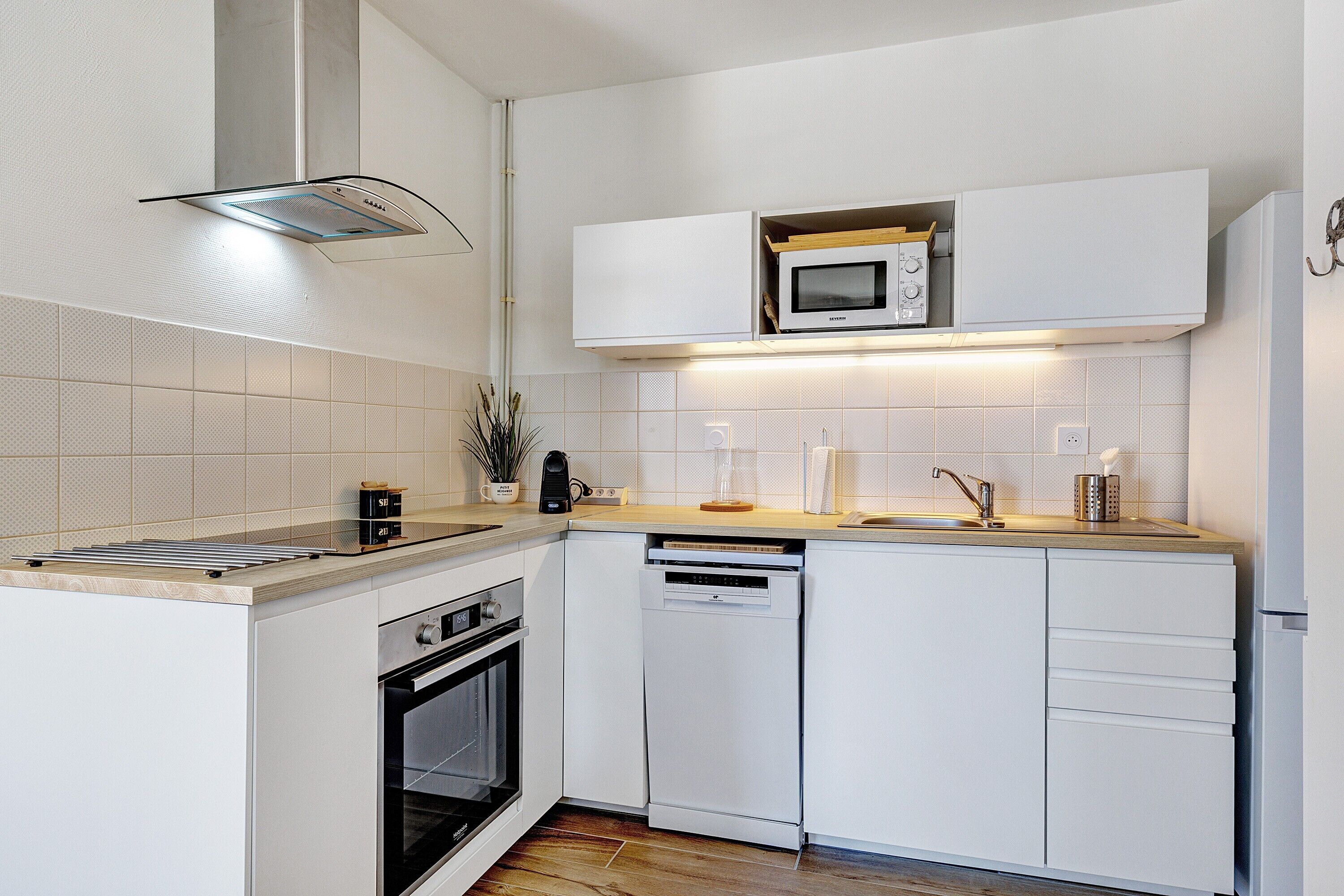 A modern kitchen with white cabinetry, a microwave, a dishwasher, and a built-in oven.