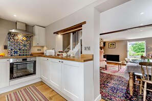 Eine moderne Küche mit weißen Schränken, einer gemusterten Spritzschutzwand und einer Holz Arbeitsplatte.