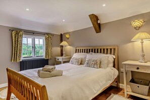 A bedroom with a bed, bedside tables, a window with curtains, and a radiator. - 2 Bed in Burwash (oc-h29338) (Burwash)