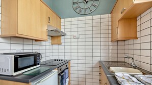 Et lille køkken med mikrobølgeovn, komfur og vask.