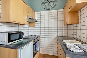 A compact kitchen with a microwave, stove, and sink. - 1 Bed in Teignmouth (oc-a29377) (Teignmouth)
