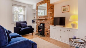 A living room with a fireplace, a television, a sofa, and a lamp. - 2 Bed in Appledore (oc-m29918) (Appledore)