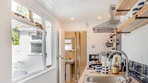 A modern kitchen with a sink, countertop, and hanging shelves. - 2 Bed in Appledore (oc-m29918) (Appledore)