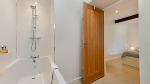 Une salle de bain moderne avec une baignoire, une douche et une porte en bois.