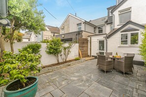 A patio with stone flooring, a dining table with wicker chairs, and a potted plant. - 4 Bed in Bude (oc-s30486) (Bude)