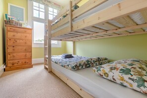 Habitación con literas, cómoda de madera y ventana.