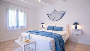 A bedroom with a bed, bedside tables, a wall hanging, and a window with curtains. - Just 50 steps from the beach: Vacation Home for 9 Guests & BBQ (Mandriola)