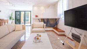 A living room with a sofa, armchair, coffee table, TV, and a hammock. - Just 50 steps from the beach: Vacation Home for 9 Guests & BBQ (Mandriola)
