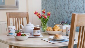 A breakfast setting with a table, chairs, a vase of tulips, a bowl of strawberries, a teapot, a jar of jam, croissants, and a cup. - 1 Bed in St. Ives (oc-g30707) (St Ives)