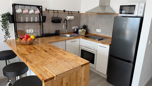 Une cuisine moderne avec un îlot central en bois, des appareils électroménagers en acier inoxydable et un réfrigérateur noir.