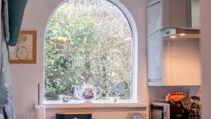 Eine Küche mit einem großen Fenster, einem Wasserkocher, einer Tasse und einem Toaster.