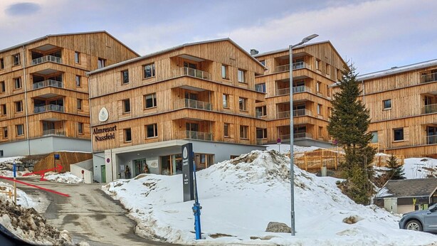 Un edificio de madera de varios pisos con balcones, con la leyenda 'Almresort Nassfeld'.
