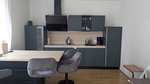 Una cocina moderna con una isla central, taburetes de bar y una mesa plegable.