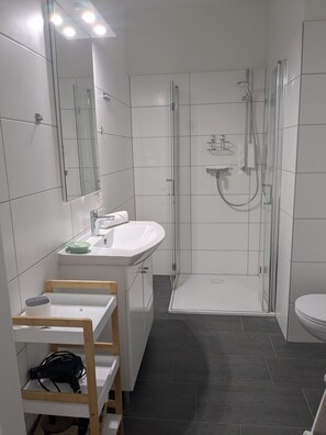 Une salle de bain moderne avec une douche à parois de verre, un lavabo blanc et un meuble-lavabo en bois.