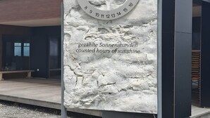 Un edificio moderno con fachada de piedra, una pantalla digital y una decoración con hoja de arce amarilla.