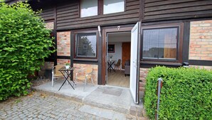 A wooden building with a brick facade, a door, and a window. - Neues Appartement im Lepels Hof (Lütow)