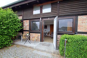 Ein Gebäude aus Holz mit Ziegelverkleidung, einer Tür und einem Fenster.