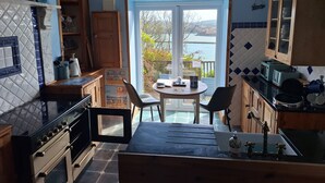 A kitchen with a view of the sea, a dining table, chairs, and a stove. - Private self catering apartment close to the stunning Pembrokeshire coast path. (Goodwick)