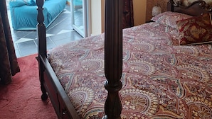 A bedroom with a four-poster bed, a chandelier, a balcony with a view, and patterned wallpaper. - Private self catering apartment close to the stunning Pembrokeshire coast path. (Goodwick)