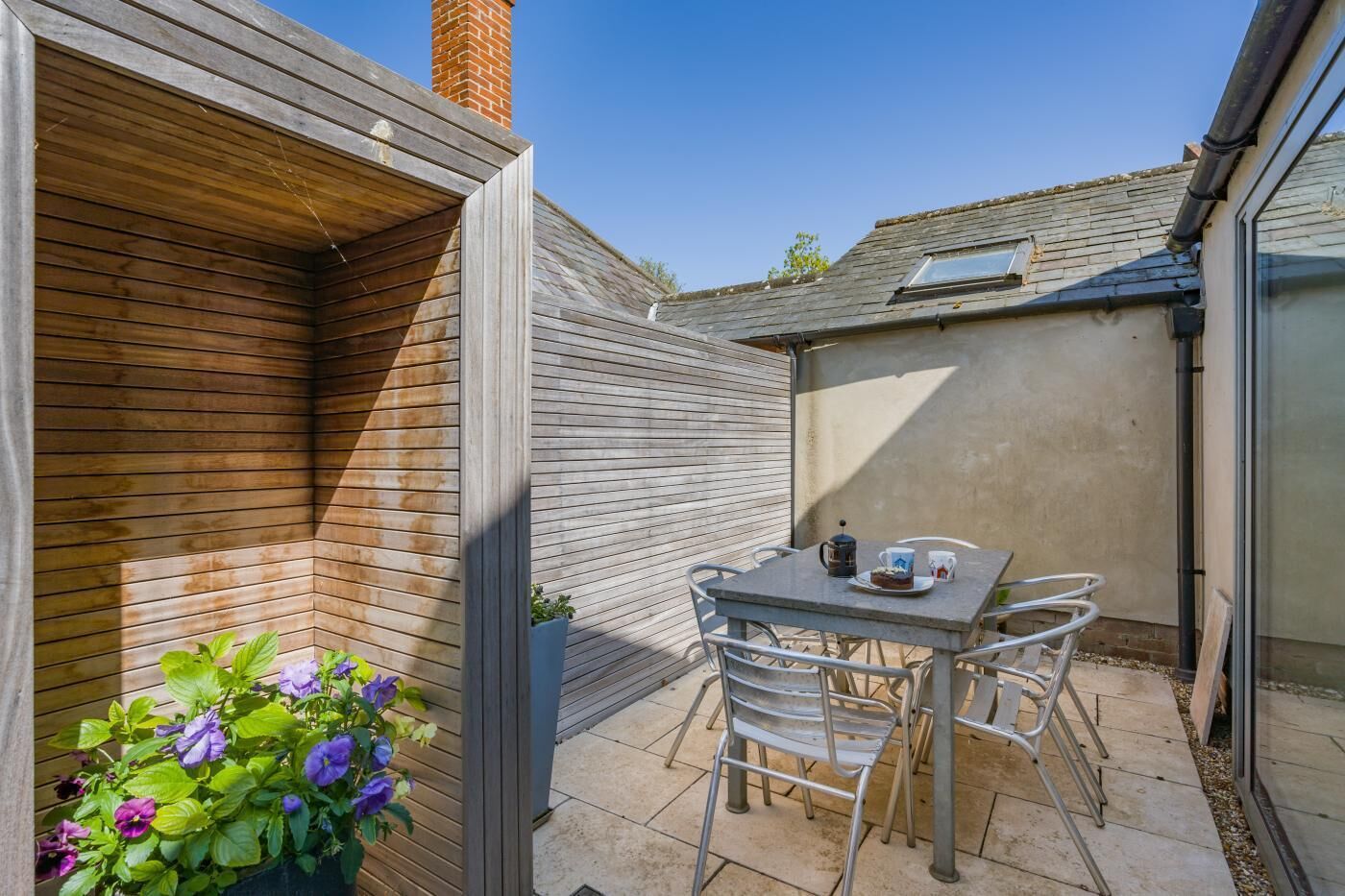 A patio with a table and chairs, a potted plant, and a brick chimney.