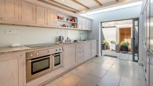 A modern kitchen with wooden cabinets, a built-in oven, and a countertop with a kettle. - 3 Bed in Orford (oc-t32016) (Orford)