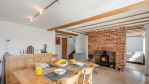A dining area with a wooden table, chairs, and a brick fireplace. - 3 Bed in Orford (oc-t32016) (Orford)