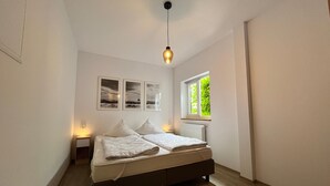 Una camera da letto con un letto, comodini, una finestra con vista e quadri appesi al muro.