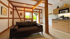 Una stanza con soffitto in legno, un divano, una cucina con mobili in legno e una finestra.