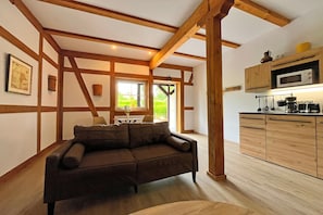 Une pièce avec un plafond en bois, un canapé, une cuisine avec des meubles en bois et une fenêtre.