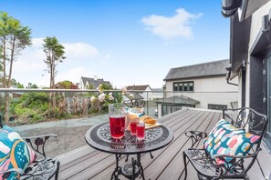 A deck with a table and chairs, a glass of red beverage, and a glass of white beverage. - 3 Bed in Innellan (oc-c32370) (Innellan)