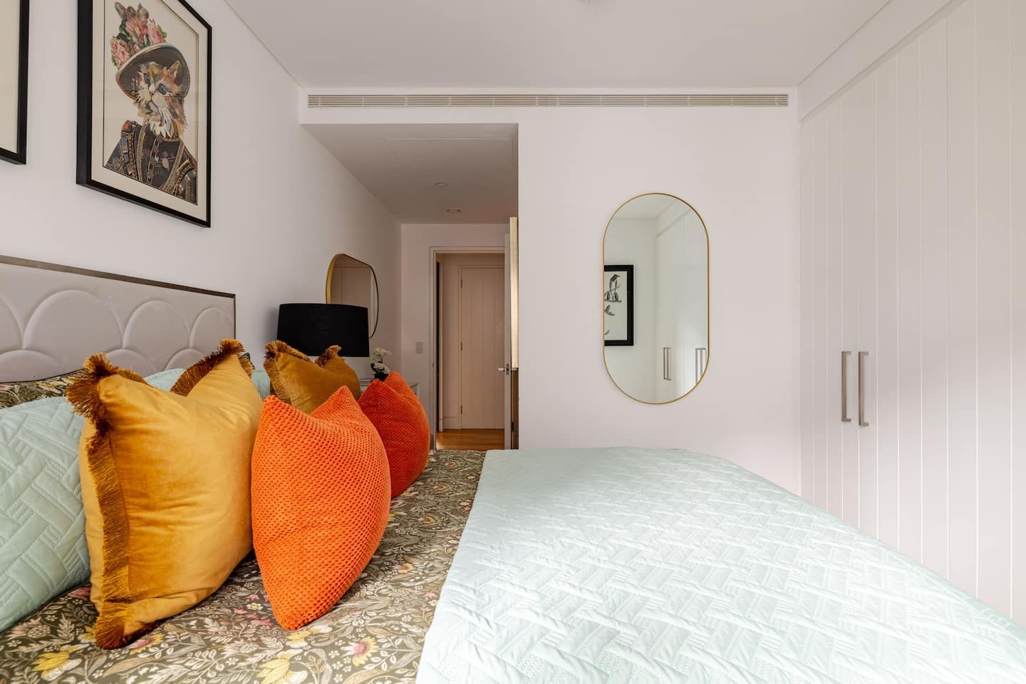 A bedroom with a bed, pillows, a mirror, and a door.